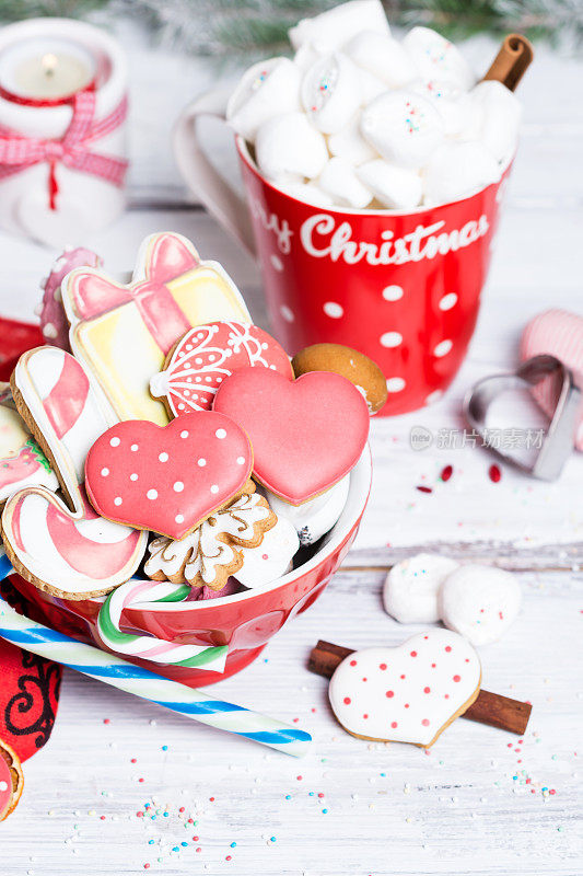 Gingerbread cookies in shape of heart, snowflake in red cup in winter composition with marshmallows in red cup with inscription „Merry Christmas“